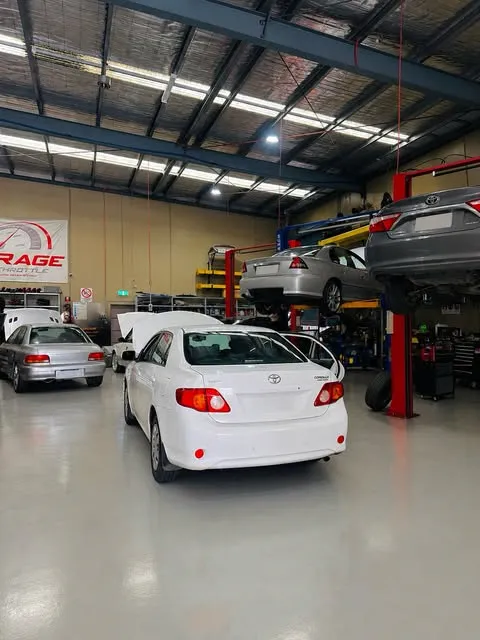 Cars on hoists inside Garage Full Throttle's Craigieburn workshop, with a white Toyota Corolla being serviced in the foreground